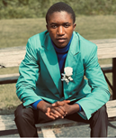 African high school student in the US - dressed in green jacket with a flower in his lapel, dressed for a wedding.