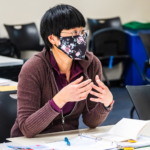 A student wearing a mask listens attentively in class