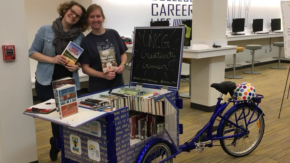 Students hold book next to the Creativity Cruiser bike