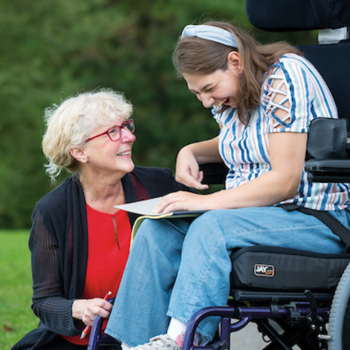 A teacher and student in a wheelchair laugh together