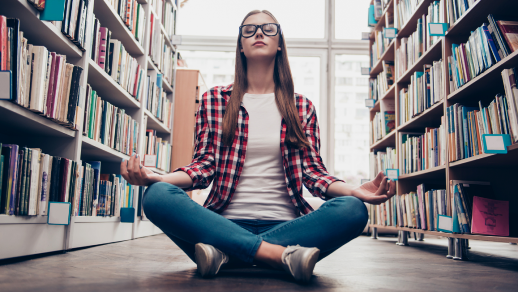 A woman meditates in a library