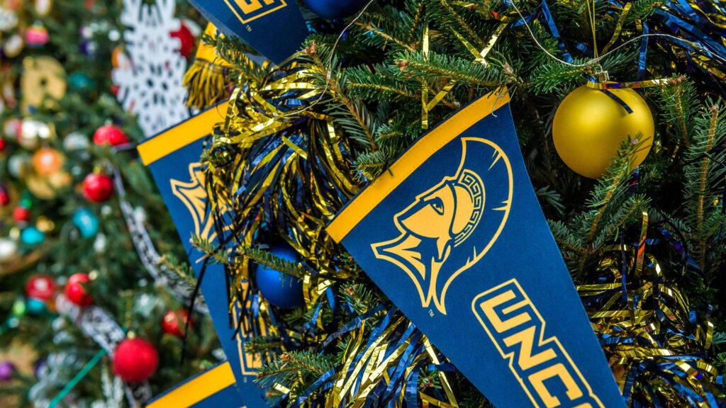 UNCG flags and ornaments on a Christmas tree.