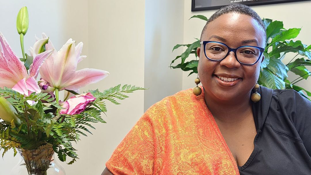 Dr. Tiffanie Lewis-Durham sits at a table next to a pink flower