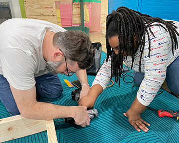 Matt Fisher, left, works with a member of the Boys & Girls Club to build a stage