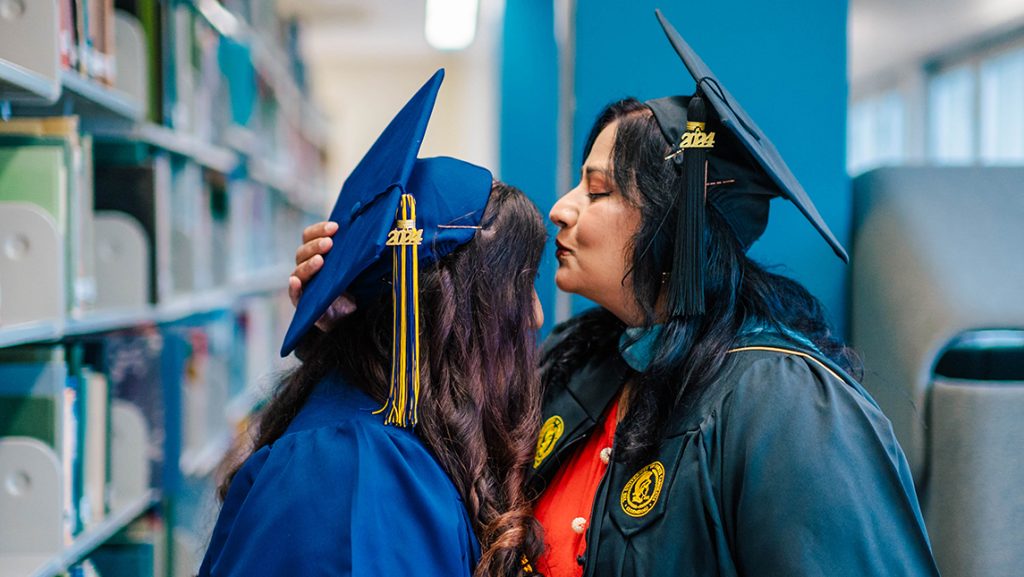 Mother and daughter graduates show affection in the library