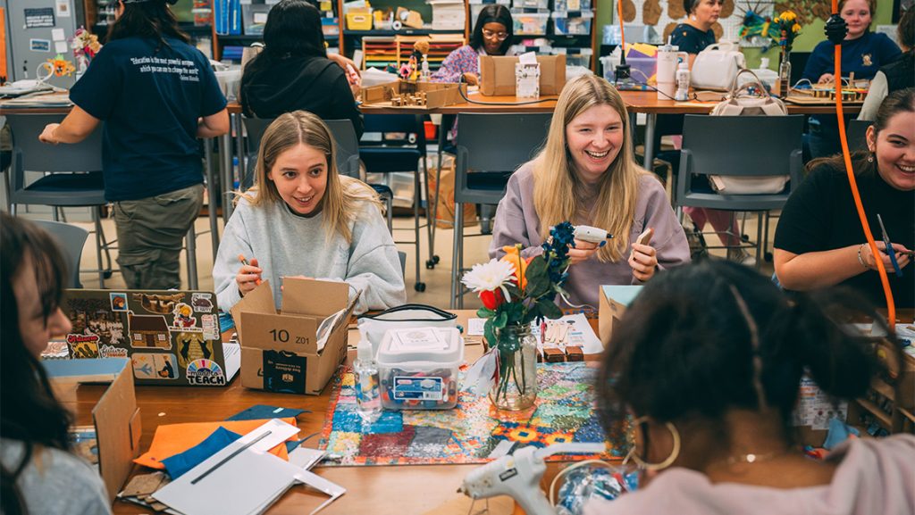 Students laugh while working on cardboard models in the SELF Design Studio