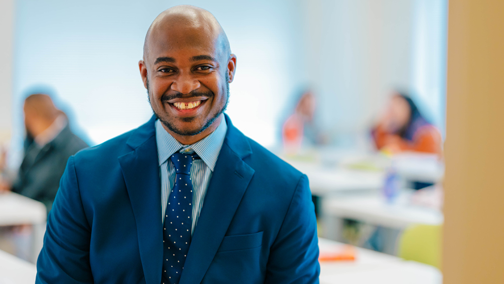 Dr. Jesse Ford poses for a headshot while a class works in the background