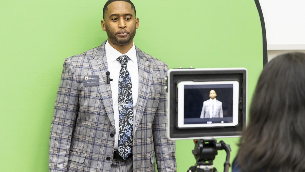 man in front of green screen being videoed by an iPad