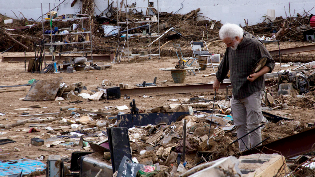 A man looks through debris left behind by Hurricane Helene