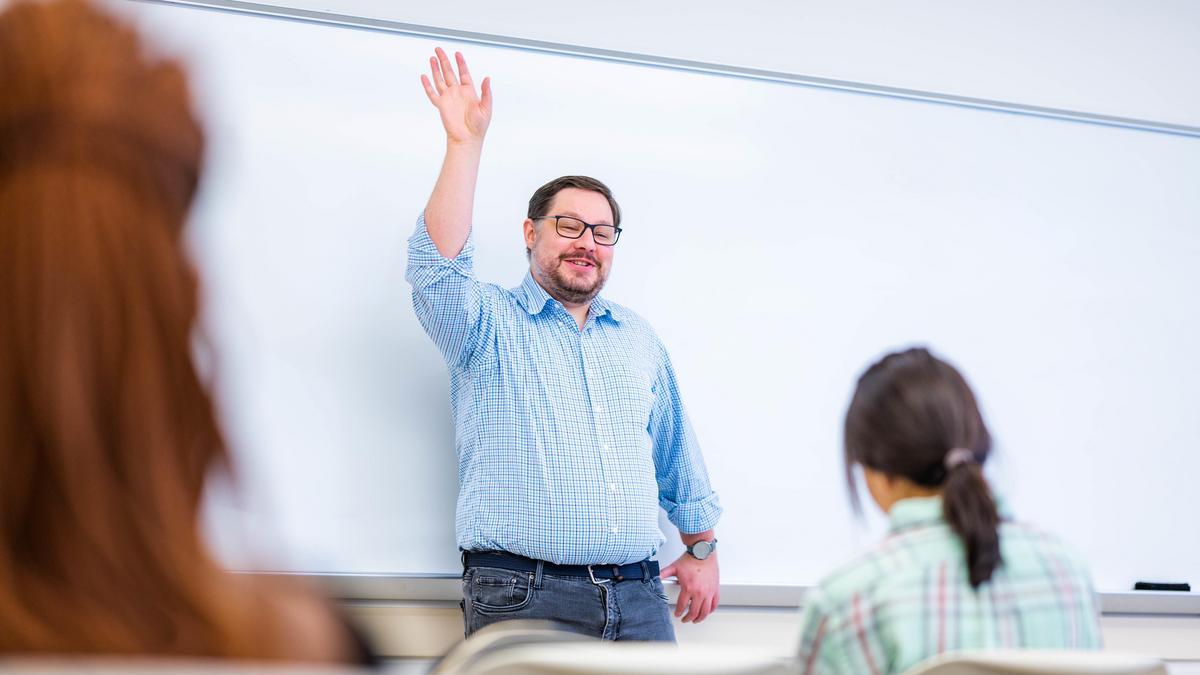 teacher with hand raised and students in classroom