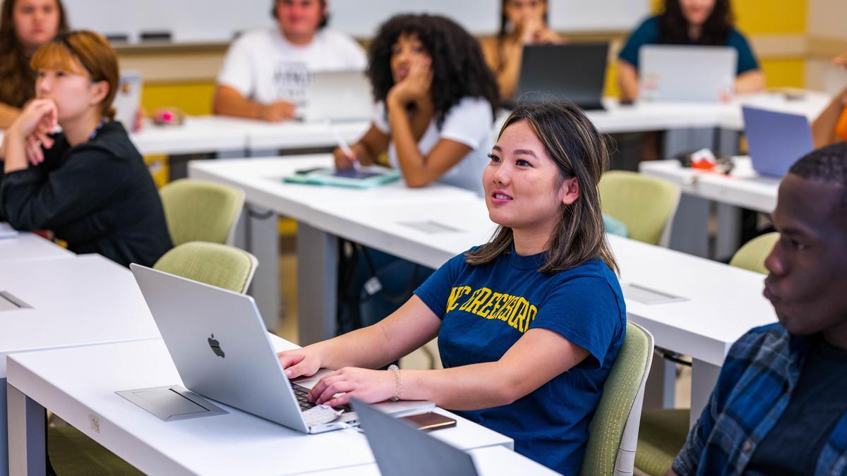 students sitting a tables with laptops