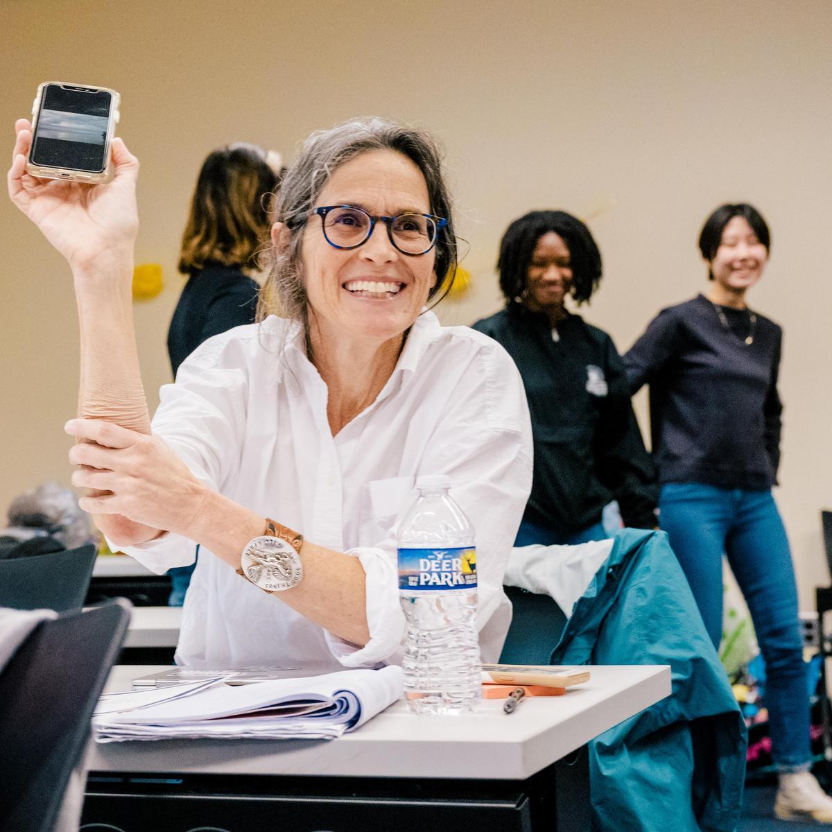Woman sitting while holding up a phone
