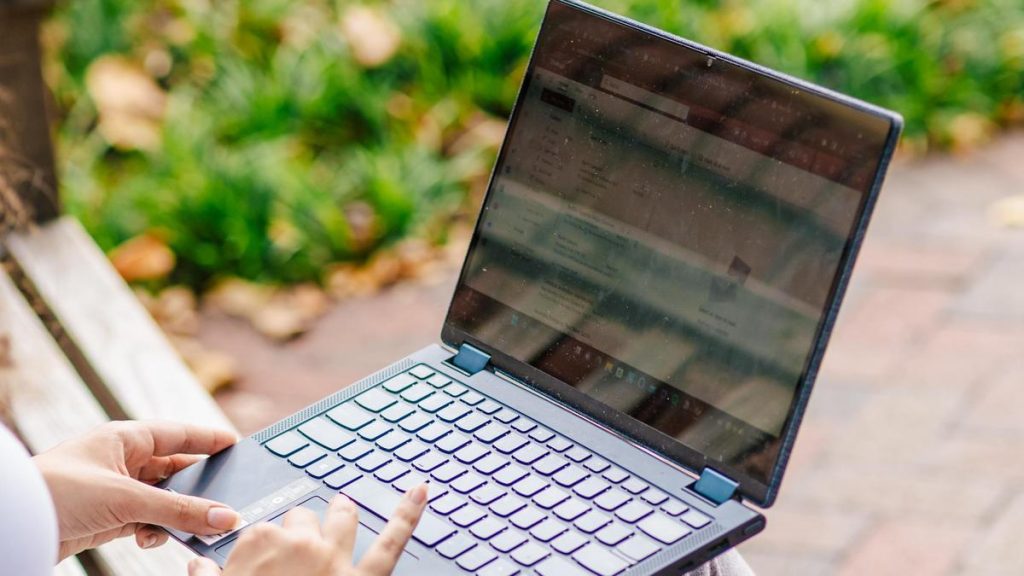 student sitting on a bench with a laptop in hand