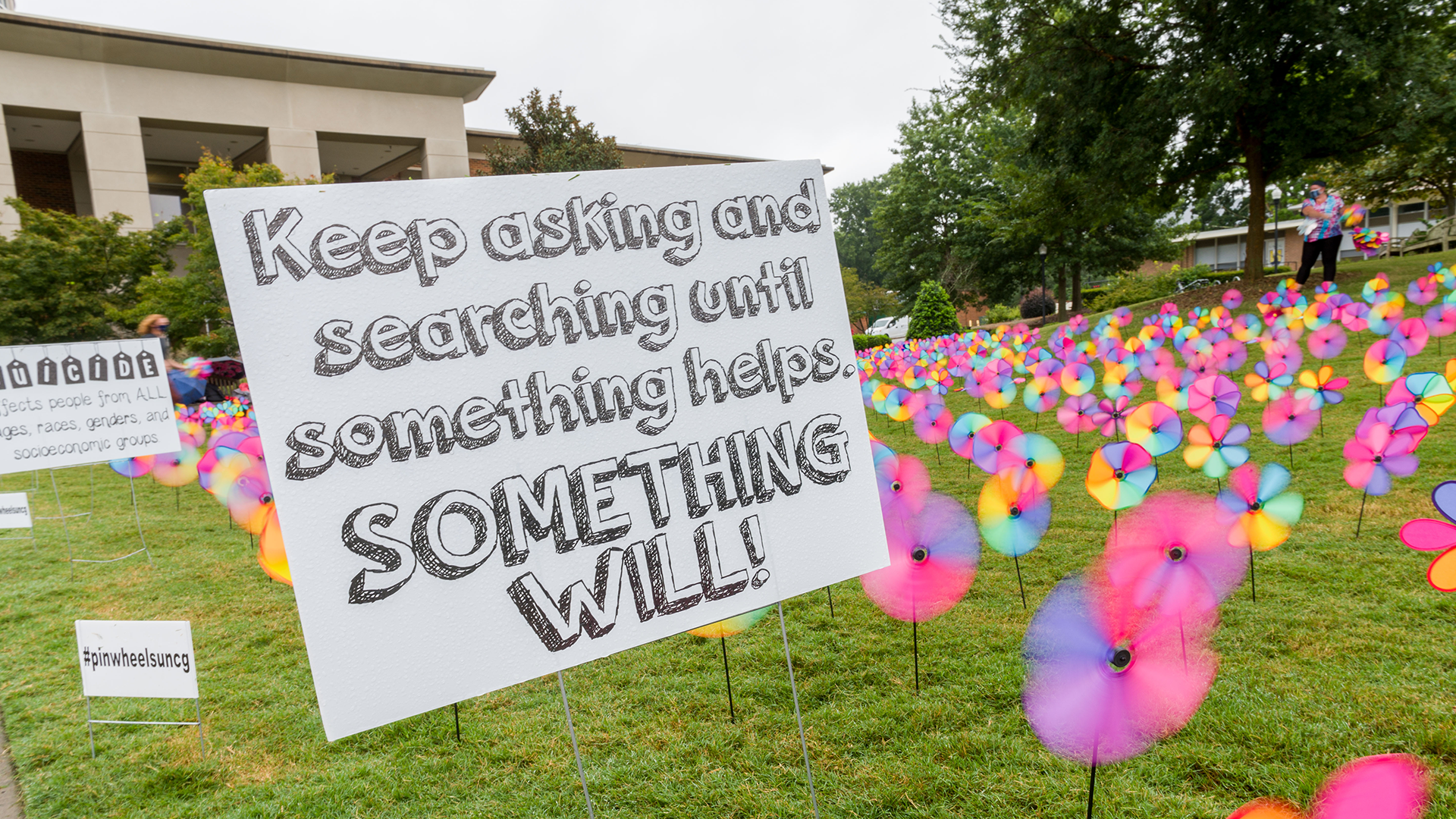 A lawn covered in pinwheels and signs related to mental health support